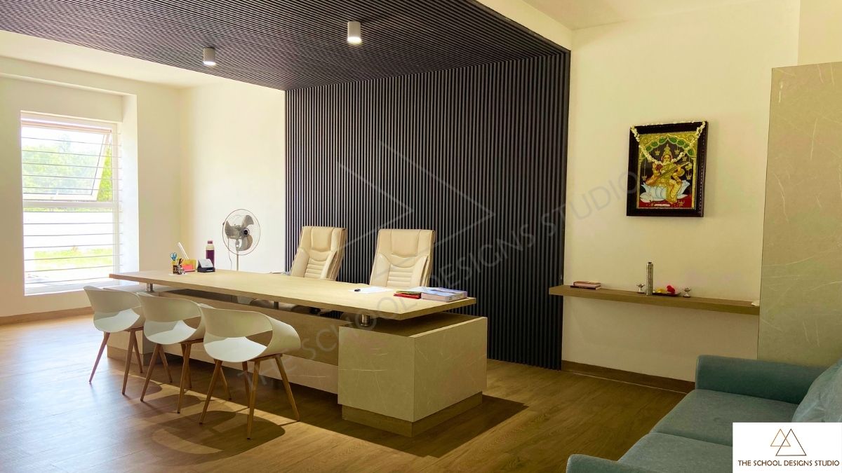 Director’s cabin interior at Pragati Vidyalaya, Challakere, Karnataka featuring modern workspace design with wooden flooring, minimalist furniture and fluted wall paneling — designed by The School Designs Studio.